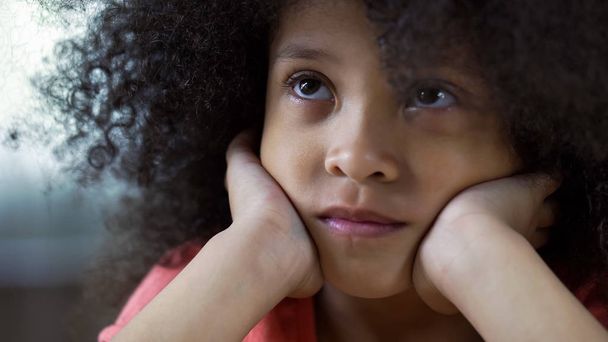 Sad lonely African-American girl looking up and thinking about family, closeup - Фото, зображення
