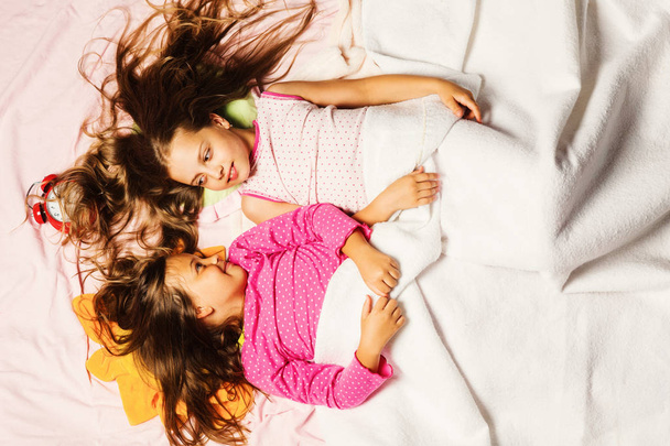 Kids in pink pajamas covered with white blanket. - Fotó, kép