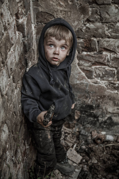 homeless dirty boy with gun in abandoned building - 写真・画像