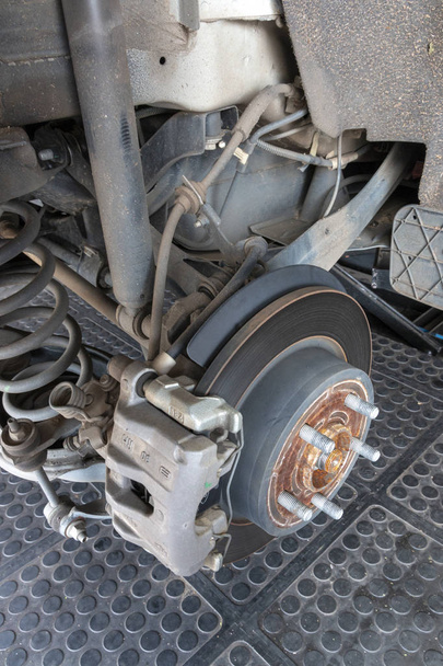 Крупный план ржавых тормозных дисков и колодок автомобиля с полным приводом, когда шины были сняты для замены
 - Фото, изображение