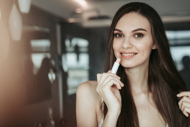 Happy female applying makeup in the apartment - Foto, afbeelding