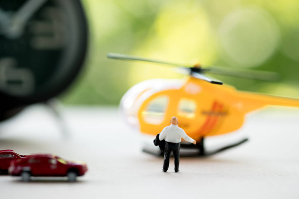 Rear view of miniature businessman walking towards helicopter. Businessman ready to pay for a helicopter rent for speed - Photo, Image