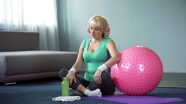 Athletic senior woman sitting yoga mat, feeling back pain, health care, injury - Фото, зображення
