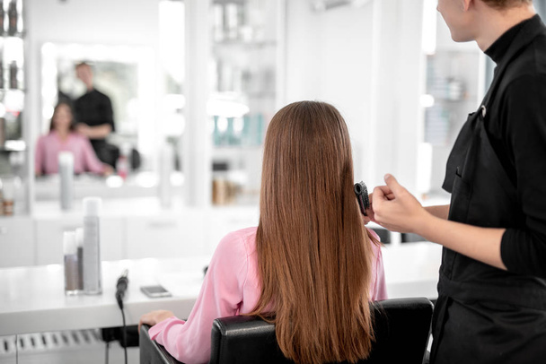 Long haired lady sitting in front of the mirror while being in beauty salon - Foto, Bild