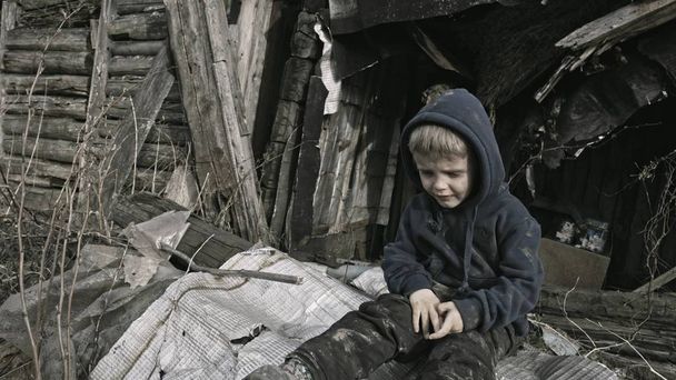 sad homeless boy sitting and frustrating in abandoned village - Фото, изображение