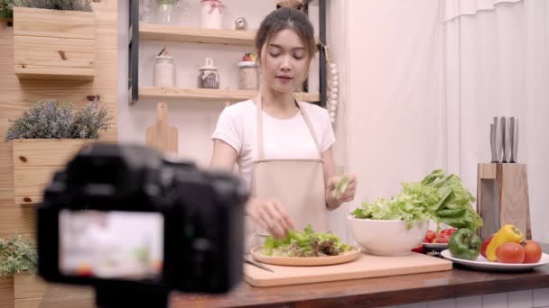 Блогер азиатская женщина с помощью камеры записи, как сделать салат здоровой пищи видео для своего абонента, женщина использовать органические овощи подготовки салат для здорового тела дома. Концепция здорового питания
. - Кадры, видео