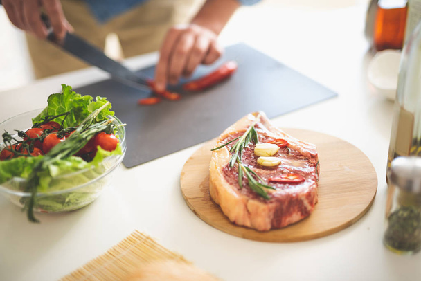 Piece of meat with various ingredients and man cooking on blurred background - Foto, immagini