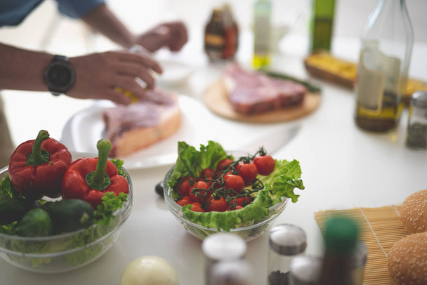 Verse groenten en man koken van vlees op onscherpe achtergrond - Foto, afbeelding