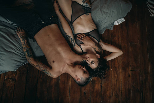 Un jeune couple à moitié nu amoureux se couche dans un câlin au lit. Vue du dessus
. - Photo, image