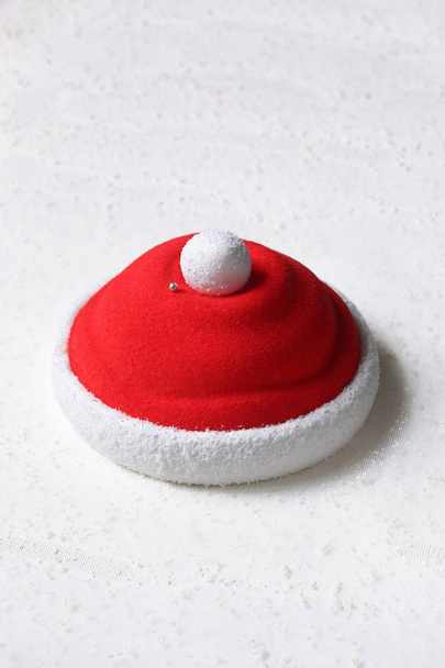 Шляпа Санта-Клауса - современный клубничный мусс торт, на белой тарелке, на белом фоне
. - Фото, изображение