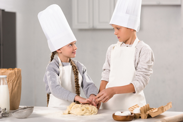 brother and sister preparing dough for cookies at table in kitchen - Photo, image