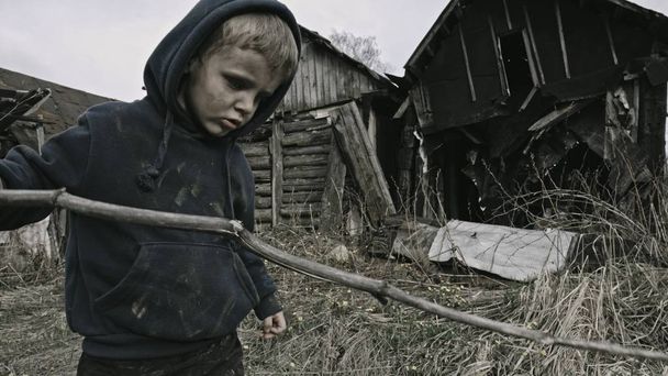 bezdomny brudny chłopiec z kijem w opuszczonej wiosce - Zdjęcie, obraz