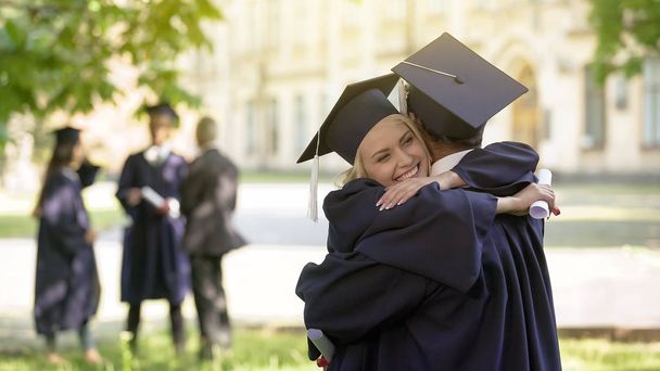 Hochschulabsolventen unterhalten sich, umarmen sich, Hochschulfreundschaft - Foto, Bild