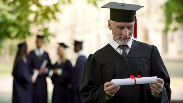 あらゆる年齢層、新しい程度で教育の卒業証書を持って学術レガリアで年配の男性 - 写真・画像