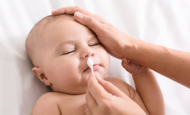 Mère nettoyage nez bébé avec coton-tige
 - Photo, image