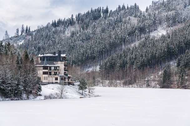 Απόμερο ξενοδοχείο κτίριο σε ένα όμορφο χειμώνα χιονισμένο τοπίο με δάση και κατεψυγμένα Brezova φράγμα - Φωτογραφία, εικόνα