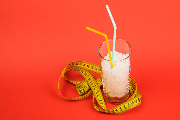 Um copo de cubos de açúcar é um conceito de comida não saudável. No fundo vermelho
. - Foto, Imagem