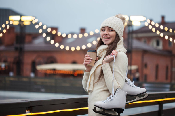 Happy young woman in knitted sweater and hat is going skating - Foto, Bild