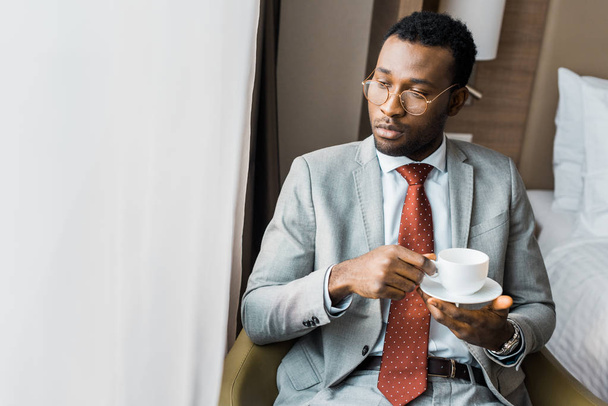 empresario afroamericano serio sosteniendo una taza de café y mirando a la ventana
 - Foto, Imagen