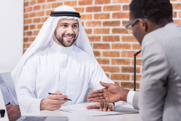 Hombre de negocios árabe firma contrato en escritorio de oficina
  - Foto, imagen