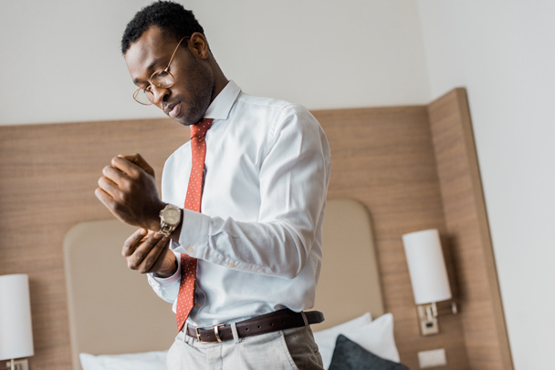 african american businessman wearing wristwatch in hotel room - Photo, Image