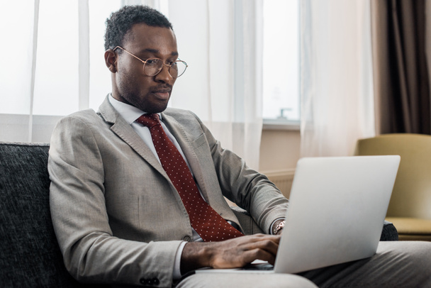 bonito homem de negócios afro-americano usando laptop no quarto de hotel
 - Foto, Imagem