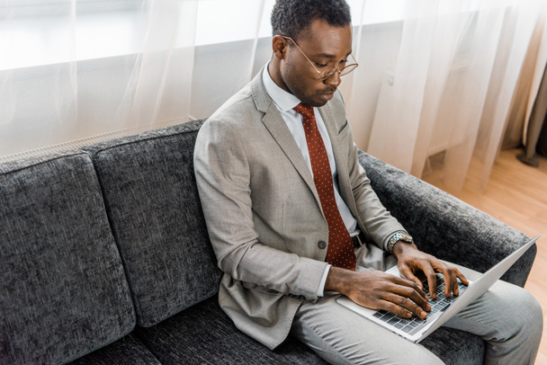 african american businessman typing on laptop in hotel room - Zdjęcie, obraz