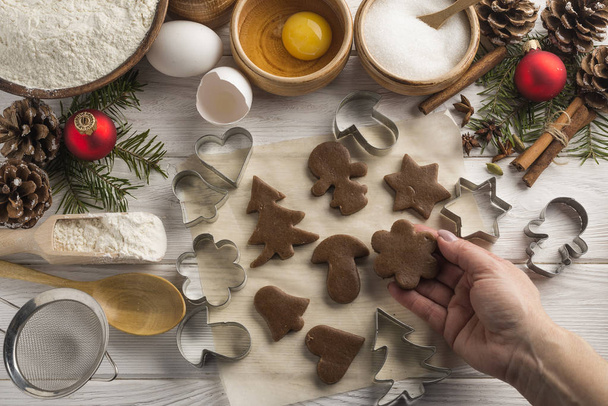 Creative fresh Christmas biscuits in woomans hand on a wooden white background. Top view. - Foto, afbeelding
