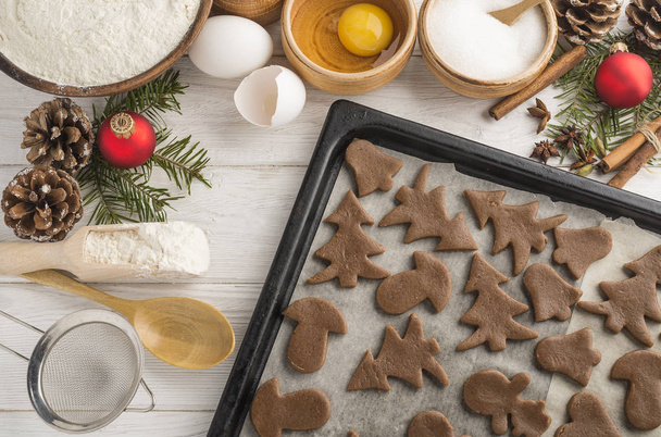 Freshly cooking christmas cookies on a baking tray on a wooden white background. Top view. - Fotoğraf, Görsel