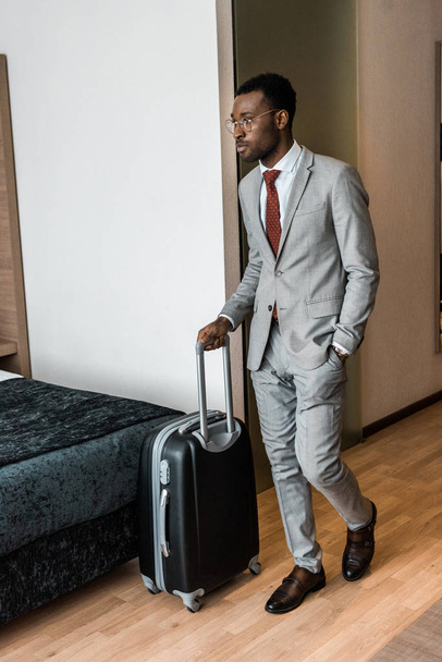 hombre de negocios afroamericano con bolsa de viaje que entra en la habitación de hotel
 - Foto, Imagen