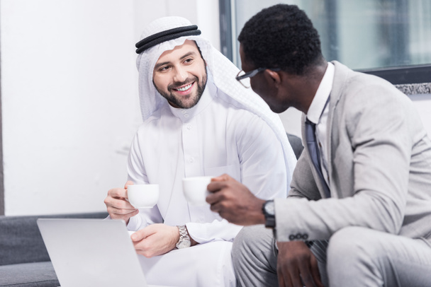 Empresarios multiculturales tomando café y hablando en la oficina
  - Foto, Imagen