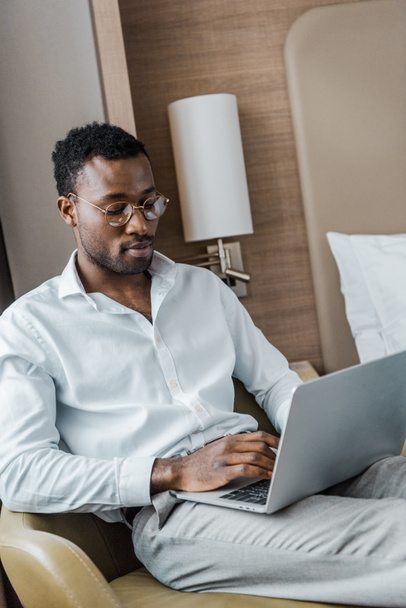 hombre de negocios afroamericano utilizando el ordenador portátil en la habitación de hotel
 - Foto, Imagen