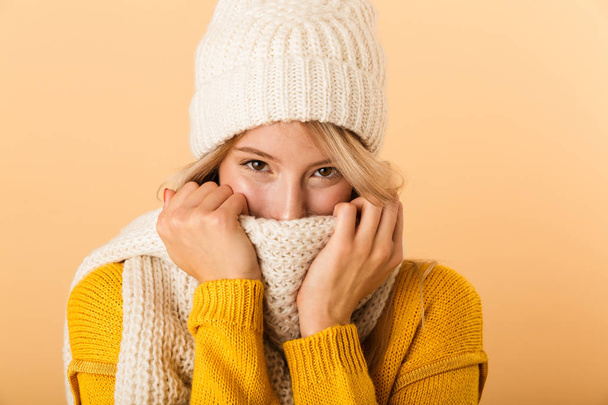Photo of a happy cute woman wearing scarf and hat posing isolated over yellow wall background. - Foto, Bild