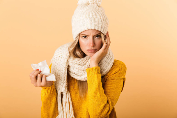 Photo of sad ill woman in plaid isolated over yellow wall background holding napkin. - Photo, Image