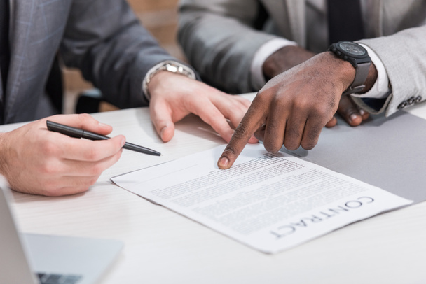 cropped view of multiethnic business partners signing contract on office table - Fotoğraf, Görsel