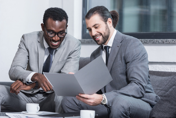 sorridente multiétnico empresários leitura documento no escritório
 - Foto, Imagem