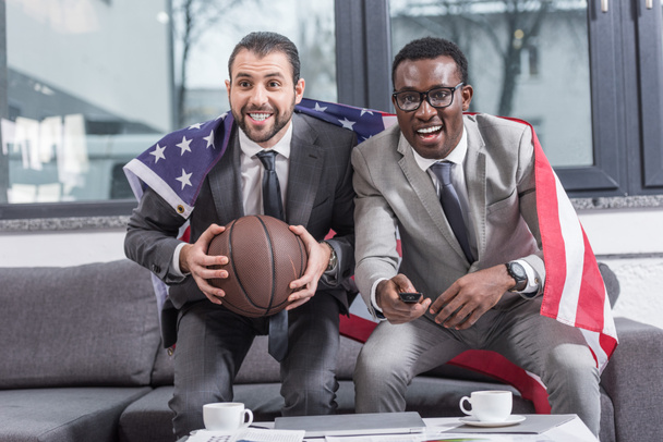 basketbol ofiste maç izlerken omuzlarında Amerikan bayrağı ile çok ırklı işadamları - Fotoğraf, Görsel