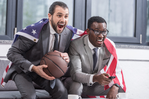 szczęśliwy wielokulturowym biznesowych partnerów z amerykańską flagę oglądania koszykówka mecz w biurze - Zdjęcie, obraz