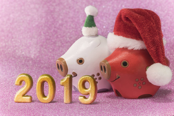 2 つのイノシシのかわいい動物の置物を年賀状やクリスマスと豚のキラキラ背景をピンクの帽子と 2019 年の手作りの黄金の番号. - 写真・画像