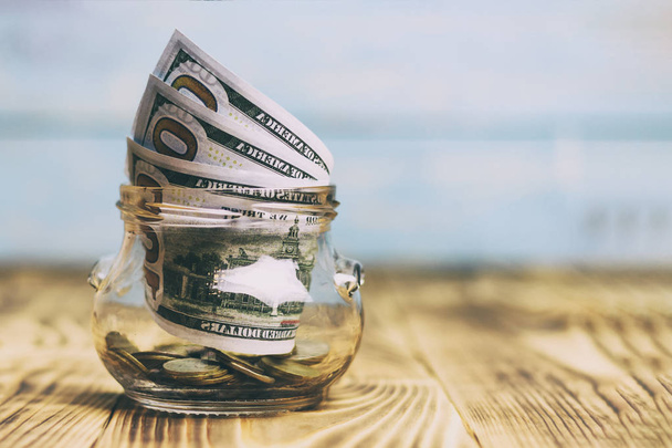 Peníze koncept, průhledného skla s bankovky dolaru na dřevěný stůl. strom je symbolem zisk, je tónování. malou hloubku řezu. - Fotografie, Obrázek
