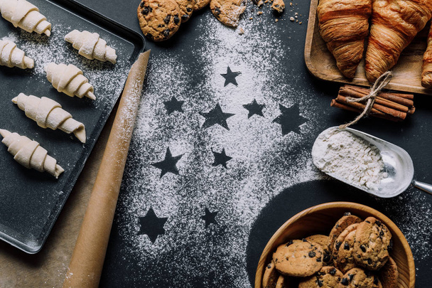 top view of tray with dough for croissants on surface covered by flour with symbols of stars  - Photo, Image