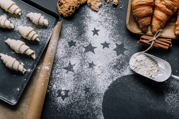 view from above of tray with dough for croissants on surface covered by flour with symbols of stars  - 写真・画像