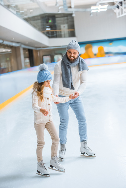 padre e hija en suéteres de punto patinando en pista de hielo juntos
 - Foto, Imagen
