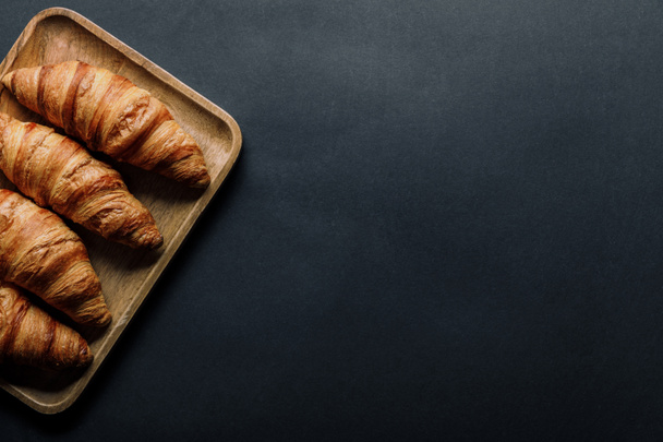 vista desde arriba de la bandeja con deliciosos croissants sobre mesa negra
 - Foto, imagen