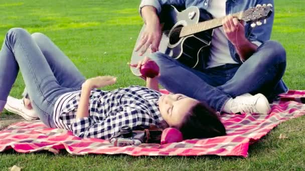 Szczęśliwa para w miłości dobrą zabawę na zielony trawnik. Facet gra na gitarze. - Materiał filmowy, wideo