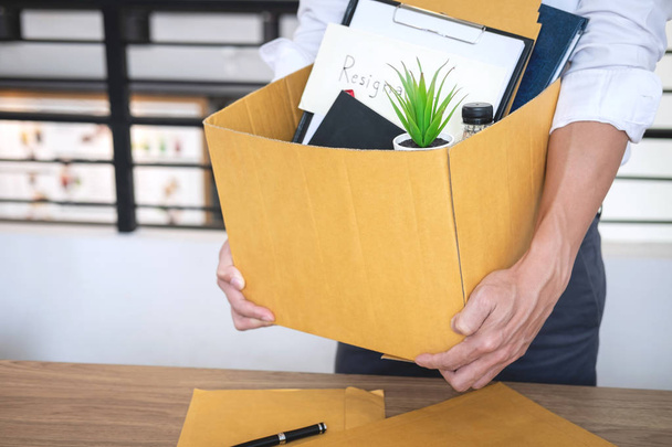 Businessman sending letter will being resignation and carrying packing belongings company and files into brown cardboard box, changing and resigning from work concept. - Photo, Image