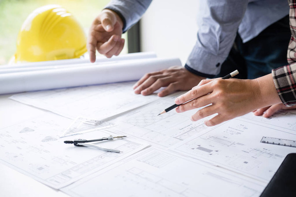 Építőmérnök vagy építész megvitatja a tervrajzot, miközben ellenőrzi az információkat rajz és vázlat találkozó építészeti projekt a munkahelyen. - Fotó, kép