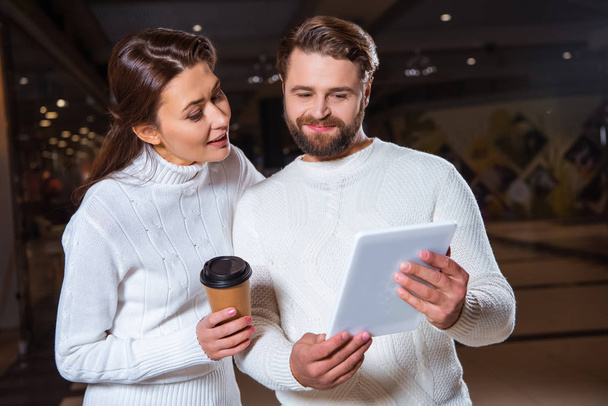 portrait of couple in white knitted sweaters using digital tablet together - Foto, Imagen