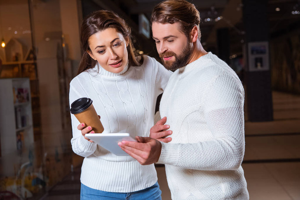 couple in white knitted sweaters using digital tablet together - Photo, Image
