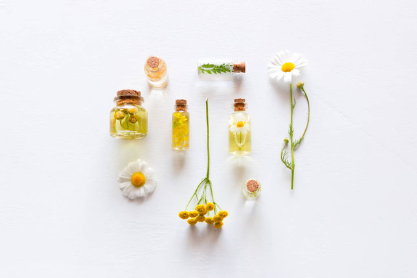 bottles with natural cosmetics for face and body care and wildflowers on a white background - Фото, изображение